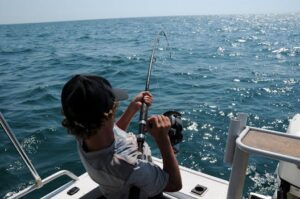 A young man actively fishing in the ocean near Broome, WA, enjoying a sunny day.