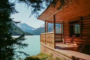Tranquil scene of a wooden cabin overlooking a serene mountain lake, surrounded by lush forest.